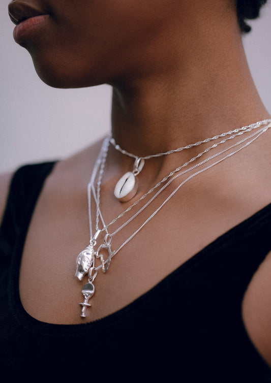 A silver necklace featuring multiple interconnected chains and charms, displayed on a person.